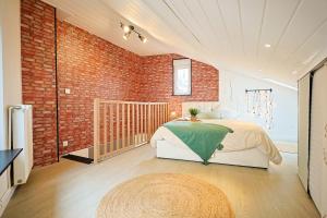 ein Schlafzimmer mit einem Bett und einer Ziegelwand in der Unterkunft La charmante maison Cosy à Saint-Avold in Saint-Avold