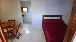 Un pequeño dormitorio con una cama y una mesa. en Chalé Lá Aurora, en Guaramiranga