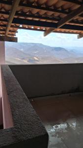 Una vista de las montañas desde un edificio con un banco. en Chalé Lá Aurora, en Guaramiranga