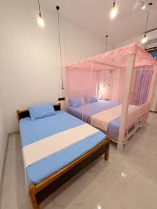 2 Betten in einem Zimmer mit Moskitonetzen in der Unterkunft Pabalu House in Ahangama