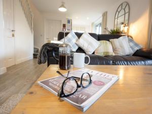 a coffee table with a book and glasses on it at Pearl & Spice Hideaways - 2 two bedroom cottages nearby - Part of the The Bay Filey Holiday Village with pool, gym and direct beach access, pub, restaurant, tennis and meadows walks in Reighton