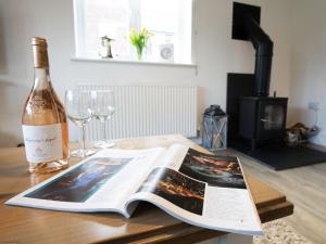 a bottle of wine and a book on a table with wine glasses at Pearl & Spice Hideaways - 2 two bedroom cottages nearby - Part of the The Bay Filey Holiday Village with pool, gym and direct beach access, pub, restaurant, tennis and meadows walks in Reighton