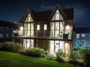 a large house with a deck at night at Pearl & Spice Hideaways - 2 two bedroom cottages nearby - Part of the The Bay Filey Holiday Village with pool, gym and direct beach access, pub, restaurant, tennis and meadows walks in Reighton