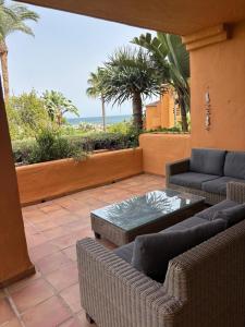 a patio with couches and a table and palm trees at Los Granados Stunning 2 Bed Beach Apartment in San Luis de Sabinillas