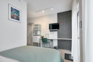 a bedroom with a bed and a desk and a television at Neubau - Citynah & Modern in Hamburg Niendorf in Hamburg
