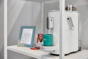 a white refrigerator with a green cup on a shelf at Neubau - Citynah & Modern in Hamburg Niendorf in Hamburg