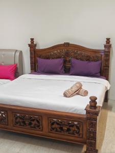 a wooden bed with purple pillows and a wooden foot board at By The Sea Beach Front and Seaview Apartment 2 in Batu Ferringhi