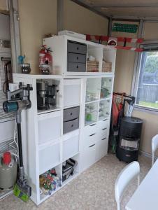 a white shelf with drawers in a room at Wohnwagen mit feststehendem Vorzelt in Fehmarn