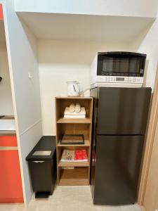 een keuken met een zwarte koelkast en een magnetron bij katsu house 心斋桥 in Osaka