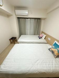 een hotelkamer met twee bedden en een raam bij katsu house 心斋桥 in Osaka