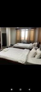 two beds in a hotel room with white sheets and pillows at Serene haven in Kohīma