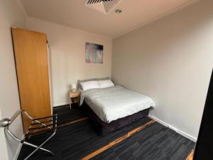 Central Melbourne 2BR Balcony Apartment في ملبورن: غرفة نوم بها سرير وكرسي