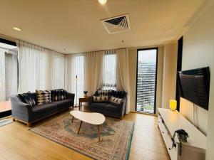 Central Melbourne 2BR Balcony Apartment في ملبورن: غرفة معيشة مع أريكتين وتلفزيون