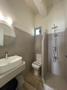 Un baño con lavabo, inodoro y espejo. en Giant Woman, en Tsoutsouros