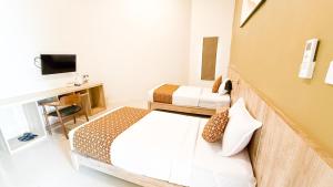 SidomuktiArtha Cottages的一间卧室，配有两张床、一张书桌和一台电视