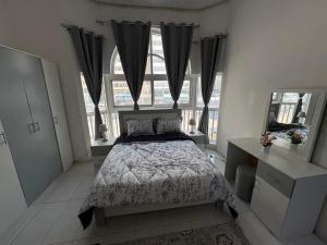 a bedroom with a bed and two windows at Lang Homes in Abu Dhabi