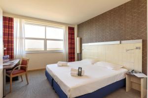 a hotel room with a large bed and a desk at B&B Hotel Cherasco Langhe in Cherasco