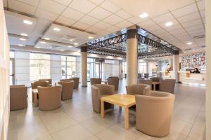 a waiting room with tables and chairs in a building at B&B Hotel Cherasco Langhe in Cherasco