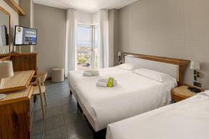 索托马里纳B&B Hotel Chioggia Airone的一间配有两张床、一张桌子和一台电视的酒店房间