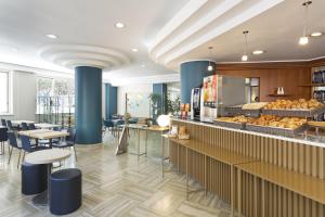 B&B Hotel Pescara في بيسكارا: مطعم ذو أعمدة وطاولات زرقاء ومخبز