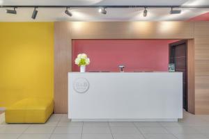 a lobby with a reception desk and a yellow bench at B&B Hotel Milano Cenisio Garibaldi in Milan