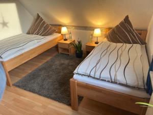 2 Betten in einem kleinen Zimmer mit 2 Lampen in der Unterkunft Ferienwohnung Winzenburg in der Nähe vom Steinhuder Meer und Dinopark Münchehagen in Rehburg-Loccum