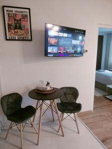 Una mesa con dos sillas y un televisor en una pared. en Apartment Hodo, en Rimavská Sobota
