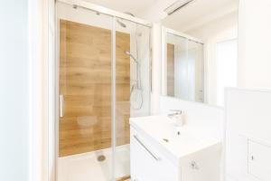 baño blanco con ducha y lavabo blanco en Cozy M3 at Pojezierska Street, en Łódź