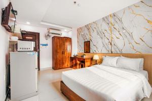 a bedroom with a white bed and a refrigerator at Kiên Cường 2 Hotel & Apartment in Danang