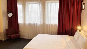 1 dormitorio con cortinas rojas, 1 cama y 1 silla en B&B HOTEL Inverness, en Inverness