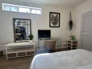 a bedroom with a bed and a desk and a television at Studio Seabiscuit in Cape Town