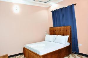 1 dormitorio con cama de madera y cortina azul en Jmapartment and shopping center, en Matemwe