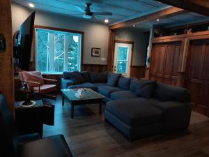 a living room with a couch and a table at Spacieuse propriété pour grande famille avec activités et spa 10 p in La Macaza