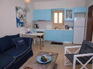 ein Wohnzimmer mit einem Sofa und eine Küche mit blauen Schränken in der Unterkunft Melograno in Kala Nera