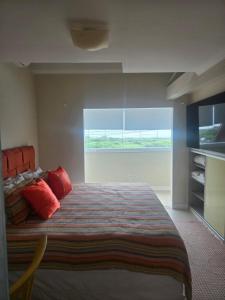 a bedroom with a bed with red pillows and a window at Casa amarela in Navegantes +26 photos
