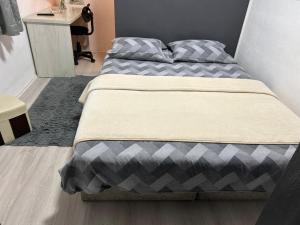 Una cama con un edredón gris y blanco en un dormitorio. en Apartmani BALKAN, en Sjenica 8 fotos más