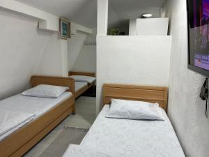 Dos camas en una habitación pequeña con en Apartmani BALKAN, en Sjenica