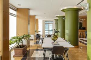 an office with green columns and tables and chairs at B&B HOTEL Cuneo Cristal in Cuneo