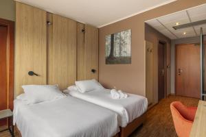 two beds in a hotel room with white sheets at B&B HOTEL Cuneo Cristal in Cuneo