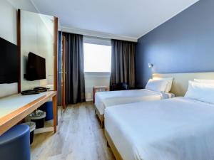a hotel room with two beds and a desk at B&B Hotel Quarto d'Altino in Quarto dʼAltino