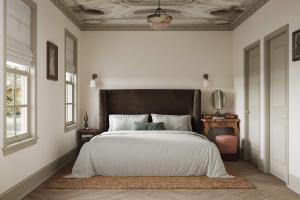 Schlafzimmer mit einem großen weißen Bett mit einem schwarzen Kopfteil in der Unterkunft Maison Foxglove - Petite Acres Chateau in New Buffalo