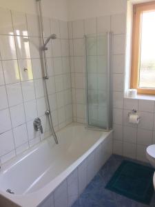 een witte badkamer met een bad en een douche bij Ferienwohnung mit Aussicht im Bergdorf Steibis im Allgäu in Steibis
