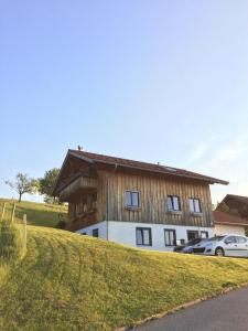 een huis op een heuvel met een auto ervoor geparkeerd bij Ferienwohnung mit Aussicht im Bergdorf Steibis im Allgäu in Steibis