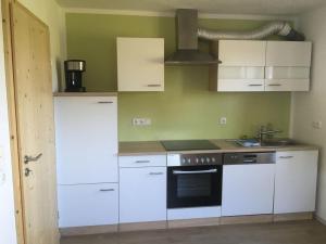 een keuken met witte kasten en een fornuis bij Ferienwohnung mit Aussicht im Bergdorf Steibis im Allgäu in Steibis +38 foto's