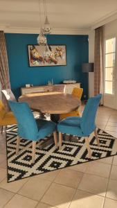 Chambre tout confort في Saint-Cyr-en-Val: غرفة طعام مع طاولة خشبية وكراسي زرقاء
