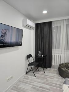 a living room with a chair and a table at Studio modern 10 min de centru, perfect pentru doi in Chişinău