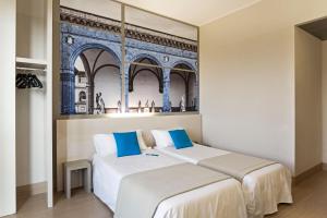 two beds in a room with a painting on the wall at B&B Hotel Firenze Nuovo Palazzo Di Giustizia in Florence