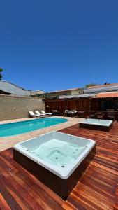 ein Whirlpool auf einer Terrasse neben einem Swimmingpool in der Unterkunft Pousada Loft Praia dos Anjos in Arraial do Cabo
