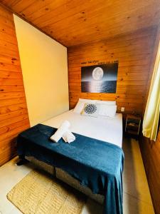 a bedroom with a bed in a wooden room at Pousada Encosta das Oliveiras in Imbituba