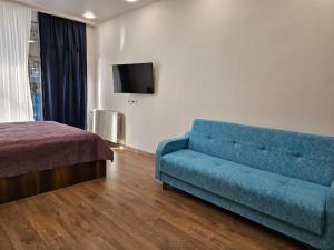 a living room with a blue couch and a bed at NBG Aparthotel in Batumi